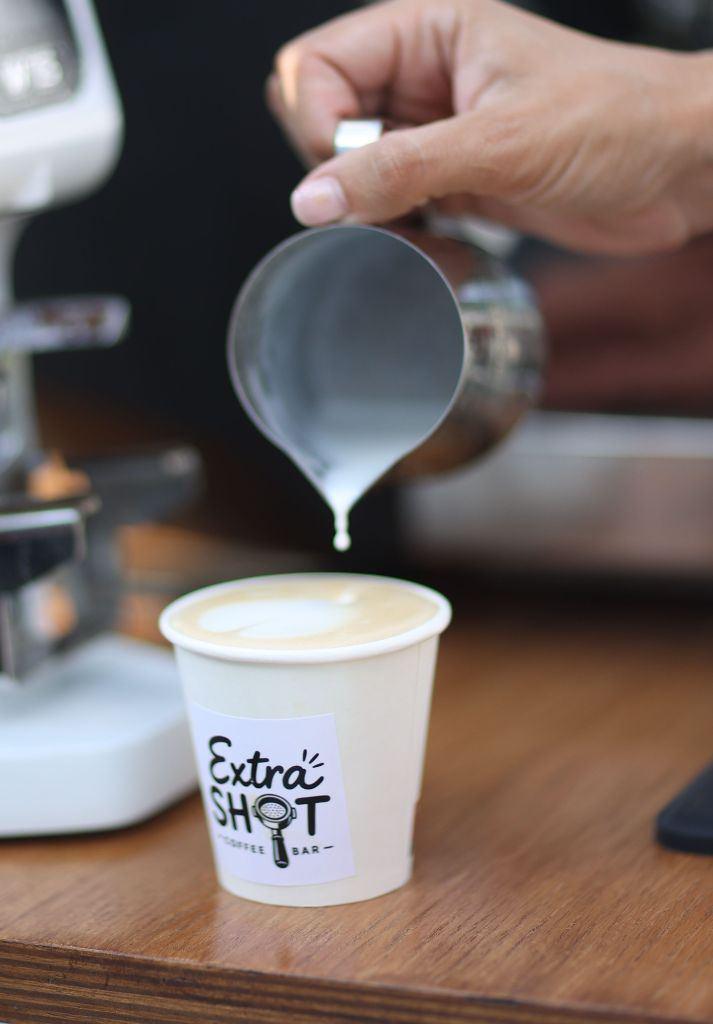 Barista pregătind o cafea, turnând lapte peste espresso